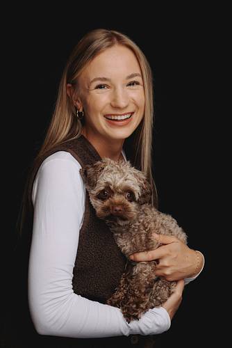 Woman smiling and holding a small dog in a photo studio – PicturePeople